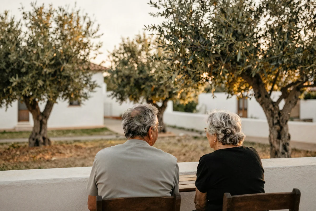 Älteres Paar sitzt auf einer schattigen Terrasse im mediterranen Nachmittagslicht